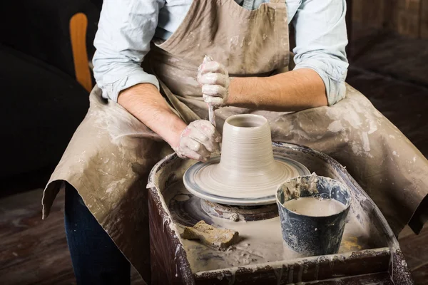 pottery, workshop tools, ceramics art concept - man hands work with potters wheel, the fingers form the shape of raw fireclay, male master sculpt a utensils with stack, profile and sponge, top view.