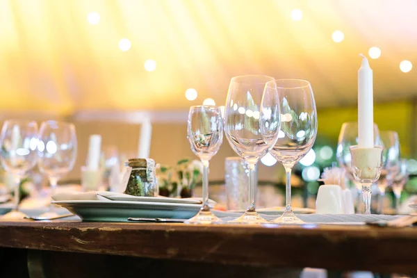 Yemek, eğlence, gece hayatı kavramı. Gümüş akıcı formlar ile dolu vintage tarzı ahşap masa üzerinde duran üç şeffaf bardak tam