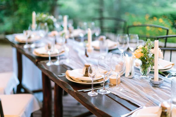Праздник, ужин, традиция. длинный дубовый стол подается для празднования с серебряными приборами, блюдами и прозрачными ослепительными бокалами, цветами и свечами в интересных держателях в виде восьмиугольных — стоковое фото