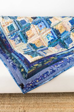 dikiş, iç mekan, patchwork, hazır giyim sanayi kavramı - muhteşem battaniye ile kesinlikle farklı çizmek, saten paçavra dikilmektedir açık ve koyu mavi tonları ile kanepede yatıyor