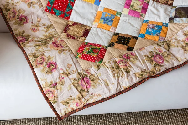 Homecraft, kunst, vintage concept. Vooraanzicht op een doorgestikte deken met vierkant en driehoek pattnern en kleurrijke print bestaan van rozen, papavers en andere soorten planten — Stockfoto