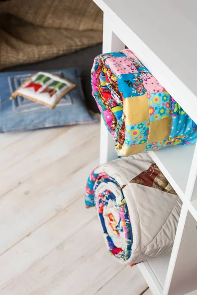 Patchwork, costura y concepto de moda: dos colchas acolchadas de colores en el estudio en estantes blancos con pocos compartimentos de almacenamiento, almacén de productos terminados, almohada en el piso, vista superior, vertical . — Foto de Stock