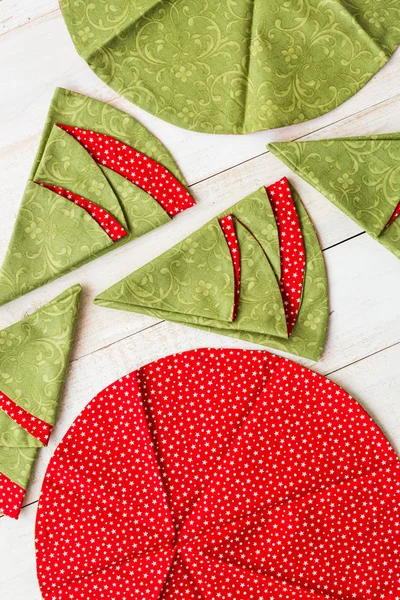 Лоскутное одеяло - крупным планом на декоративных красно-зеленых салфетках на побеленном деревянном полу, праздничные вышитые полотенца в форме кругов и рождественских елок, вид сверху, плоская укладка . — стоковое фото