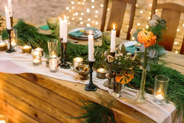 rahatlık, kutlama, gümüş kavramı. çok parlak ışıklar ve Ladin ve birkaç turuncu gül taze dalları ile restoran yanan mumlar dekore edilmiş aydınlatmak tablosu