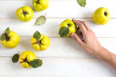 sağlıklı gıda, beslenme, bitki kavramı. Görünüm parlak iyi meyve yeşil yaprakları ile top ve karanlık Kalpler, onlar beyaz masanın üzerinde yerleştirilir ve erkek el onlardan biri alıyor