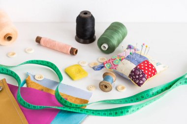 Araçlar closeup, patchwork, terzilik ve moda kavramı dikiş - ölçme bant, iş parçacığı makaralar, iğnelik, düğmeler, makas, renkli patchwork kumaş parçaları, beyaz masanın üstüne sabun.