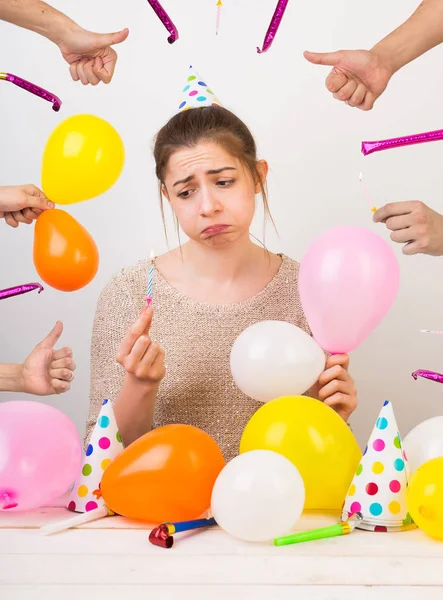Emocje, uczucia, koncepcja party urodziny. bardzo smutna dziewczyna zaniedbany, który się dąsa, ona jest otoczony przez kolorowe balony, czapeczek z kropkami, ręce z kciuki i gwizdki — Zdjęcie stockowe