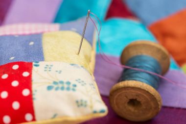patchwork, kapitone, dikiş, dikiş ve moda kavramı - yakın çekim güzel renkli dikişli minder ve iğne, makro mavi, Lila ve kırmızı flep kumaşın arka plan ile yastık üzerinde.