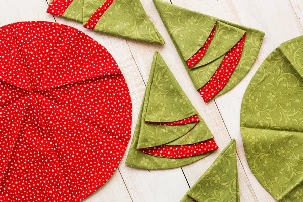 Patchwork e conceito de costura macro de guardanapos decorativos vermelhos e verdes no chão de madeira caiado de branco, toalhas bordadas festivas em forma de círculos e árvores de Natal, vista superior, flat lay . — Fotografia de Stock