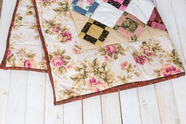 çarşaflar, sıcak, diğerleri kavramı. Küçük Çift yığın ahşap zemin üzerinde yalan geometrik figürler ile çerçeveli süsleme tarafından dekore edilmiş çiçekli baskı ile maded battaniye el