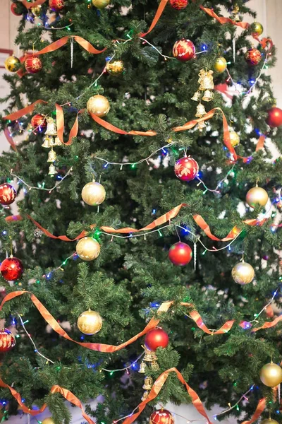 Feriados, natureza, celebrando conceito. abeto preparado para a árvore de natal e cuidadosamente decorado com bolas maravilhosas em diferentes cores, luzes e fitas vermelhas — Fotografia de Stock