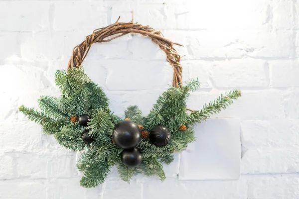 축 하, 겨울, 전통 개념입니다. 크리스마스는 백색 벽돌 벽의 배경에 화 환 침 엽 수 나무의 유연한 지점의 weaved와 작은 pinecones와 검은 공을 장식 — 스톡 사진