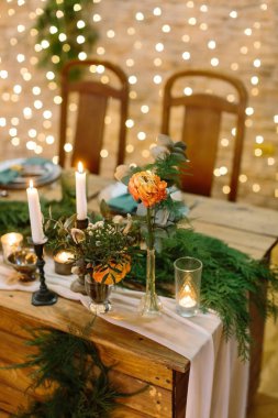 Dekorasyon, masa düzenleme, çiçek tasarımı konsepti. Masanın kenarında farklı yapraklardan ve yükselen güneşin renginde harika güllerden oluşan birkaç demet vardır.