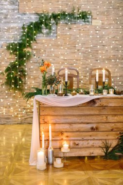 Restoran, servis, tasarım konsepti. Duvarlarda parıldayan ışıklarla süslenmiş bayramları kutlamak için alan ladin dalları ve gül demetleri gibi çeşitli bitkiler.