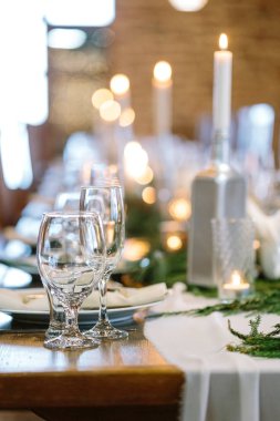 Masa düzenleme, iç tasarım, eğlence konsepti. Ateş ışıklarının mavi arka planında farklı şekillerde şeffaf bardaklar var. Çeşitli içecekler için tasarlanmış boyutlar.