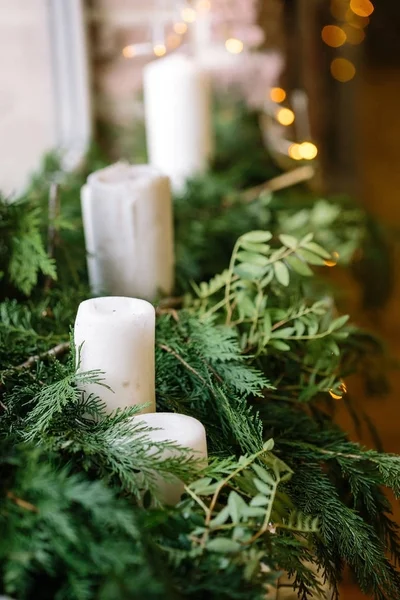 wedding decoration, environment, christmas concept. close up of white fat unlighted candles of different sizes that are drowning in the fresh green conifers bunches