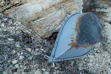 Balıkçılık, yelkencilik, kış konsepti. Bir sürü küçük ve büyük taş, kum ve yapraksız dallar arasında kaya ve eski gri balıkçı teknesinin bir parçası var.