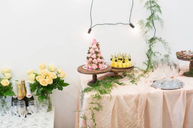 Düğün, kutlama, tedavi kavramı. Mükemmel çiçek ve ışıklar ile dekore edilmiş ve şişe şampanya, gözlük ve tatlı ile servis birkaç tablolar vardır