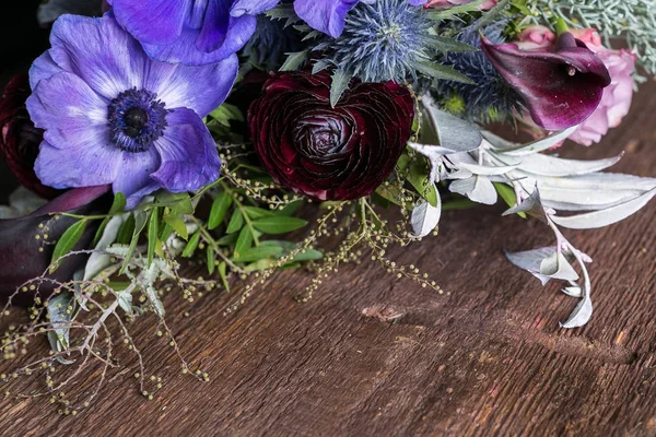 Arreglo de flores, boda, concepto de plantación. sobre la mesa de madera oscura hay un ramo de flores en varios colores, lila, marrón, rosa oscuro, todas las flores mezcladas con hojas decorativas —  Fotos de Stock