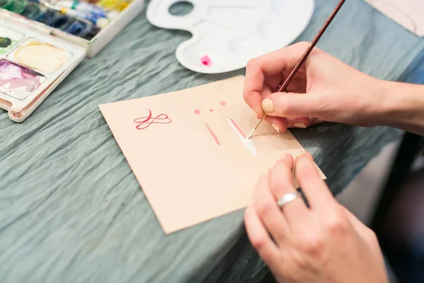 Pyssel, rita, hobby konceptet. närbild av vapen av kvinnlig konstnär med snygg manikyr och silver ring, hon håller en borste i vit färg och rita en bild med watercolores — Stockfoto