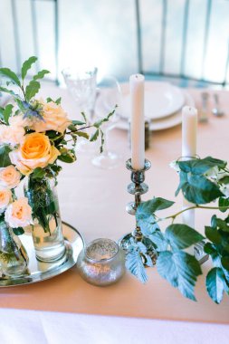 ayar, yemek, çiçek tasarım konsepti. orada beyaz tabak, çatal bıçak, çok yeşillik ve küçük demet gül ve küçük ve büyük sahipleri kaç mum farklı türde