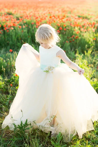 Girl model, poppies, fashion, summer nature concept - pretty blonde girl dance in the sunny field of poppies, she is in white wedding dress with beautiful blue belt decorated with flowers. — Stock Photo, Image