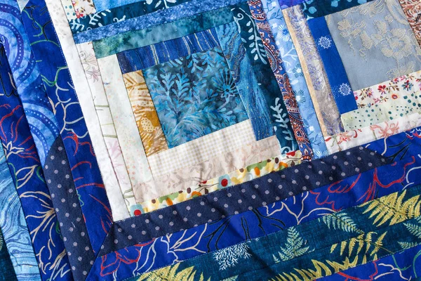 Handgemaakt, naaien, patchwork, stoffen, voorliefde concept - diepblauwe kussen naaide voor verschillende katoenweefsel met aquarel bloemen, rode en roze lijnen, stippen en bossige bladeren van varens — Stockfoto