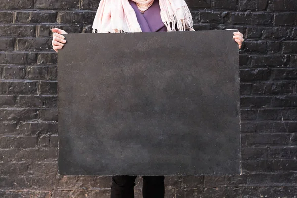 background, negative space, arts and crafts concept. close up of small and clean school blackboard in the arms of woman that is holding it on the edges