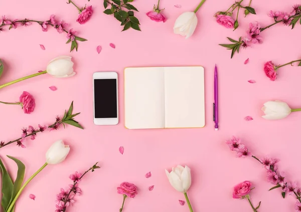business lady, office, freelance concept. top view of the most important things for businesswoman, there is mobile phone and small clean planner for composing daily life, they are placed among flowers