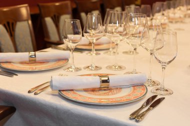 Tören, düğün, dekorasyon konsepti. Kutlama için servis edilen restoranın lüks sofra takımlarının kapısında şeftali rengi tabaklar, parlak bardaklar, gümüş bıçaklar ve çatallar var.