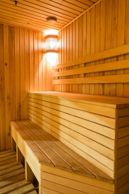 Atmosfer, dekor, rahatlama konsepti. Buhar banyosunun köşesinde merdiven gibi ahşap banklar var. Oda yumuşak ışıkla aydınlatılmış.