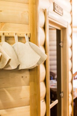 Spa, sağlıklı yaşam, ekipman konsepti. Duvarda doğal ahşapkalarla süslenmiş yün şapkalar var. Buhar banyosu ve güzellik prosedürü için özel olarak hazırlanmış.