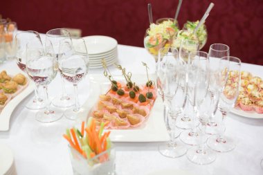Dekorasyon, tatiller, düğün konsepti. Kutlama masasında çeşitli atıştırmalıklar, pembe kağıt bardaklar ve uzun şarap kadehlerine konmuş salatalar var.