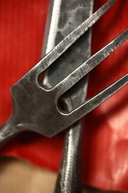 Gümüş takımlar, dekorasyon, yemek konsepti. Yüzeyde kahverengi ve kırmızı kağıtlarla kaplı aynı malzemeden yapılmış bıçağın üzerine yerleştirilmiş bir çatal var.