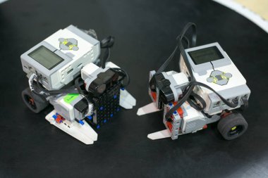 Teknoloji, icat, makine konsepti. Özel test platformunun siyah yüzeyine yerleştirilmiş iki robotu kapatın. Küçük ekranlar, tekerlekler, kablolar ve düğmelerle donatılmışlardır.