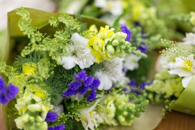 Büyüme, çiçek dekoru, düzenleme konsepti. Renkleri ve gölgeleri farklı olan küçük çiçekleri kapatın. Bunların arasında dekoratif yeşil yapraklar ve bitkiler de var.