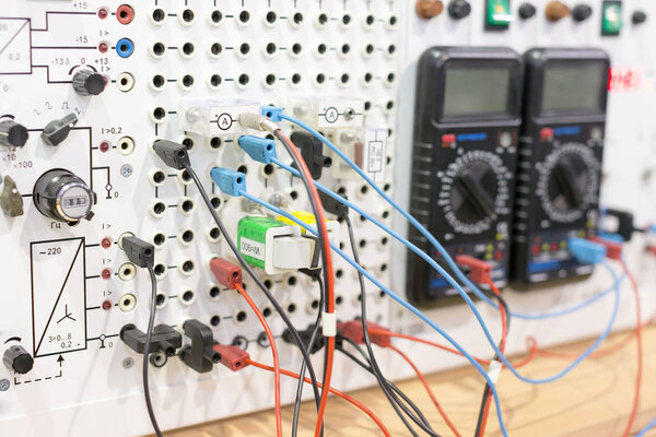 electricity, equipment, science concept. close up of wires in different coloures that connect this electric device and two multimeters with small screens and controllers