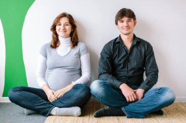 Aile, gevşeme, konsept spor. bir kadın ve bir adam ağacın yeşil boya ile duvar tarafından katta oturan, hamile