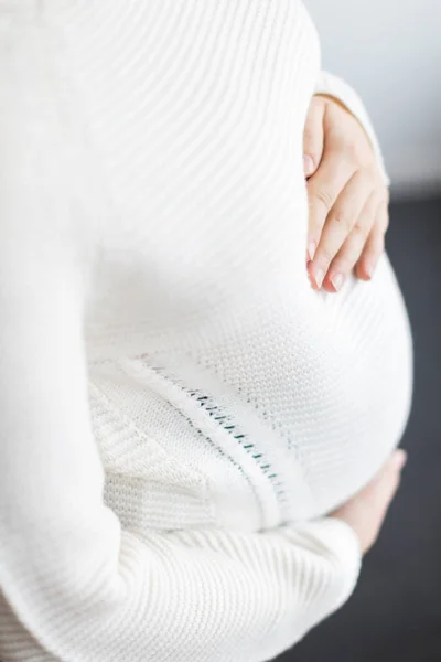 未来, 怀孕, 母性的概念。她的肚子上有一双手裹着针织毛衣, 她怀孕了, 这就是为什么她温柔地拥抱她的肚子 — 图库照片