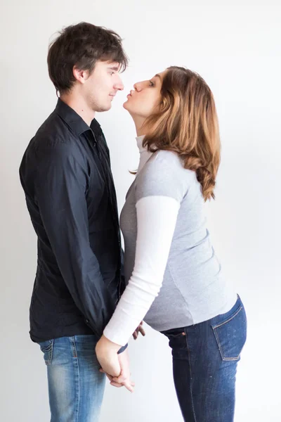 Embarazo, sentimientos, concepto de cuidado. hay una pareja cariñosa, que se están divirtiendo y jugando entre sí, ella está usando suéter gris y jeans y él está en la camisa y jeans —  Fotos de Stock