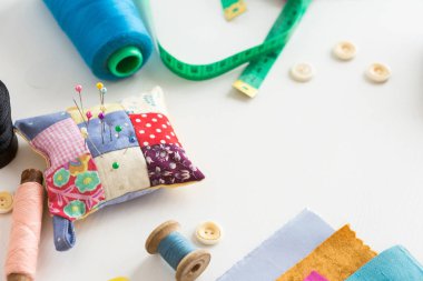 örgü işi, el işi, dikiş ve terzilik konsepti - beyaz masaya yakın araçlar, ölçüm göstergesi, mavi, pembe ve siyah iplik makaraları, renkli kumaş kırıntıları, iğneler ve iğneler, beyaz düğmeler