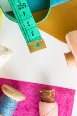 yama işi, dikiş ve terzilik kavramı - araçlara, ölçüm sayacına, bobinlerdeki mavi ve pembe ipliklere, beyaz arka planda mor ve hardal rengi yamalarına, üst görünüme, düz yere, dikey