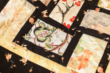 Dikiş dikme, el işi, konsept. Çiçeklerin, yaprakların ve meyvelerin rengarenk desenlerinden oluşan farklı parçalarla dikilmiş muhteşem bir battaniyenin üzerini kapatın.