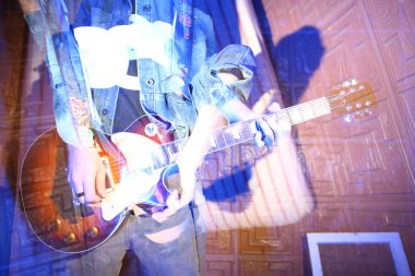 Gösteri, gösteri, yetenek konsepti. Elinde rock gitarı olan bir erkek müzisyen var, belirsiz figürü parlak ışıkla aydınlanan mavi arka planda kayboluyor.
