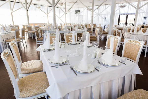 decor, party, catering concept. there is one of the numerous table, it is prepared for celebrating wedding, covered with perfect white cloth, all napkins on the plates are like towers