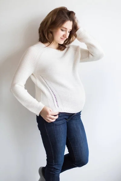 Moda, maternità, concetto di bellezza. c'è una bella donna vestita in stile minimalista in abiti comodi come maglione morbido bianco e jeans blu scuro — Foto Stock