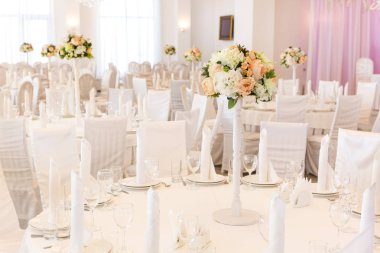 Restoran, parti, ziyafet konsepti. Restoranda düğün günü için dekore edilmiş bir masa var. Her şey beyaz ve gün ışığında parlıyor.