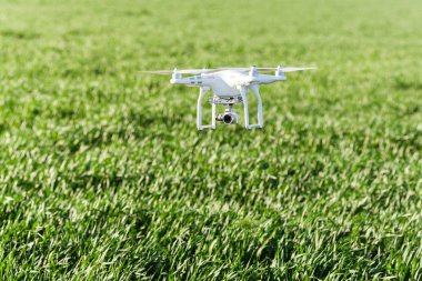 dört pervane ve kurmak-içinde yaz çim sahası, quadrocopter kalkış üzerinde arka plan dijital kameraya beyaz uçak uçan düşük quadcopter açık havada, havadan görüntüleri ve Rekreasyon kavramı-.