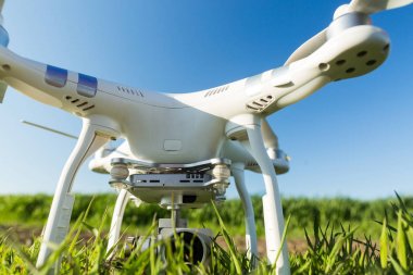 quadcopter açık havada, havadan görüntü ve teknoloji hobi, eğlence kavramı - quadrocopter arka plan mavi gökyüzü, beyaz portre uçak gövde ve kamera üzerinde yaz çimenlikte kalkışa hazır.