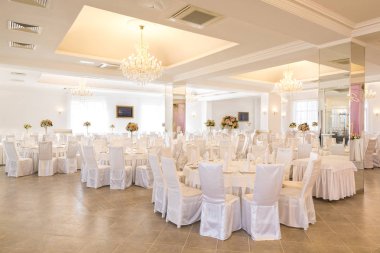 Nişan, kutlama, parti konsepti. Düğün günü için salon var, muhteşem avizelerin ışığında parlıyor çünkü tüm masalar, sandalyeler, duvarlar ve tavan karlı beyaz.